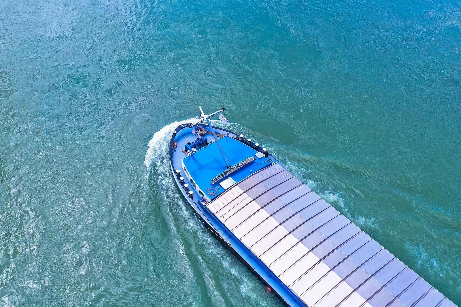 Blaues Binnenschiff auf einem Wasserweg, von oben gesehen